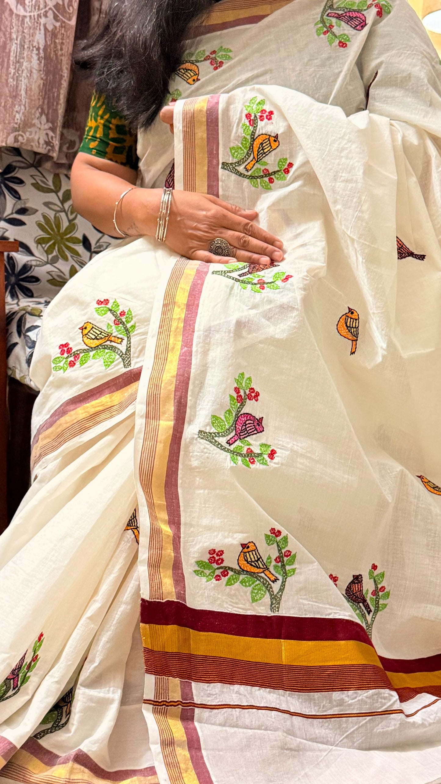 Close-up display of Sujni embroidery with colourful birds perched on flowering branches on ivory Kerala Cotton
