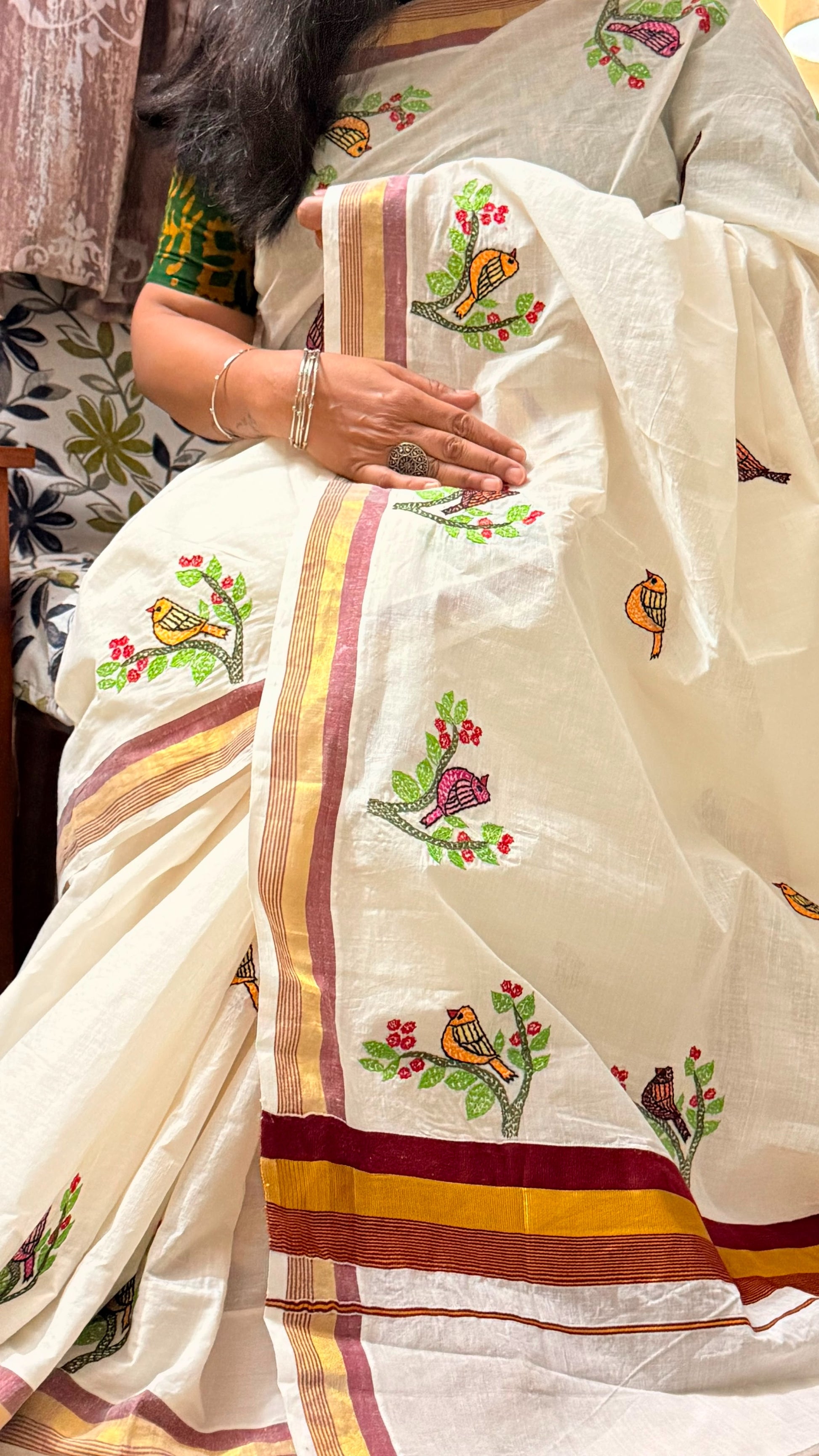 Close-up display of Sujni embroidery with colourful birds perched on flowering branches on ivory Kerala Cotton