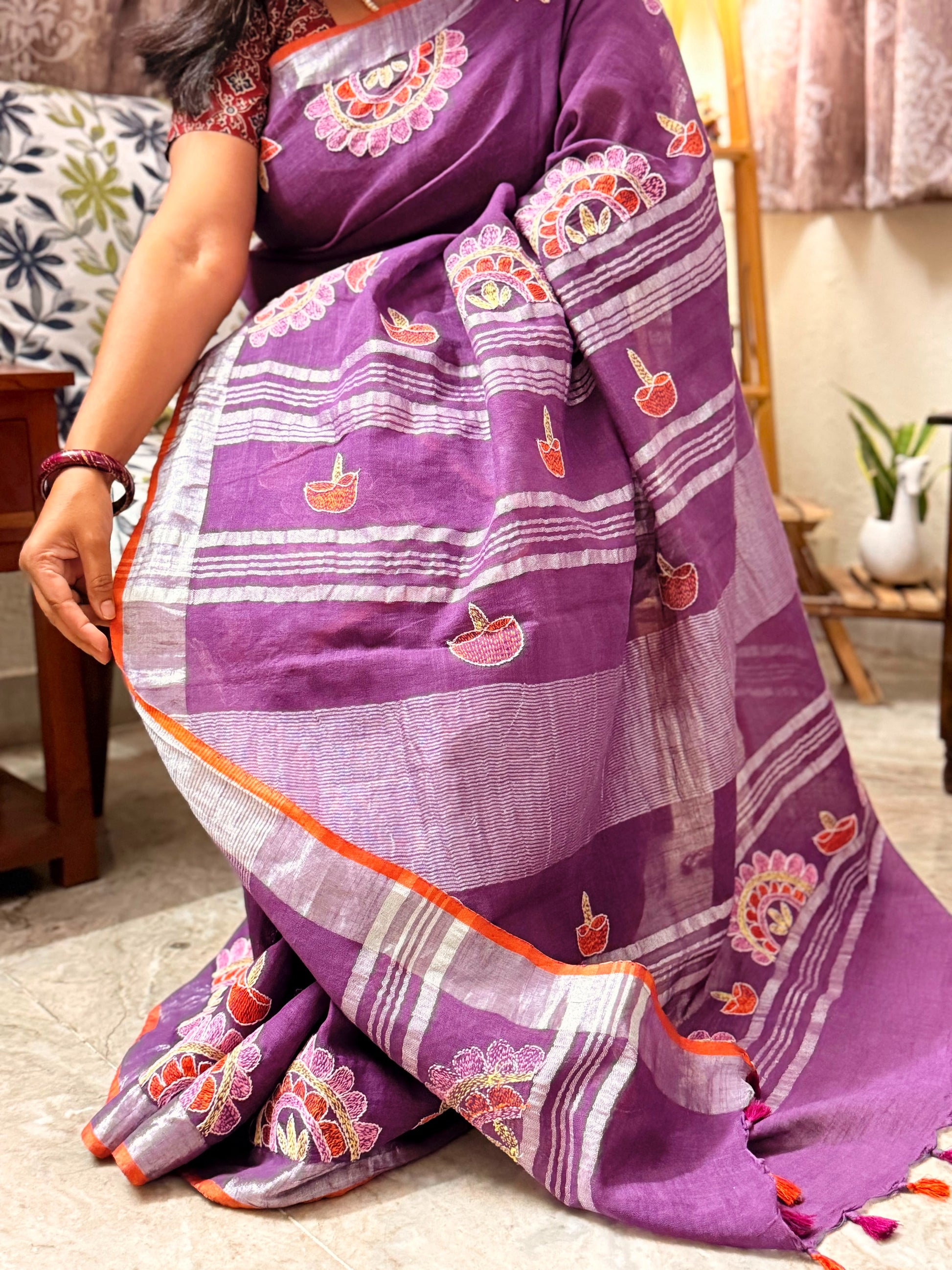 Close-up of hand embroidered diya motifs on royal purple linen saree
